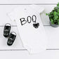 White baby romper with black writing saying Boo and spider