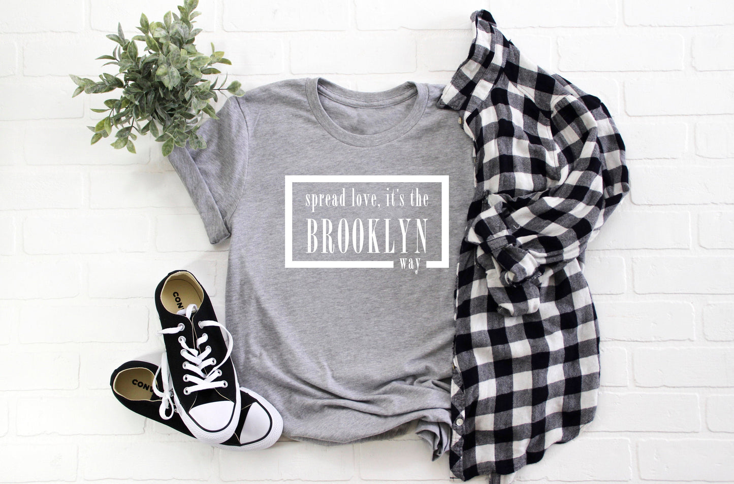 Grey t-shirt with white writing that has Biggie lyrics that states Spread love, it's the Brooklyn way.